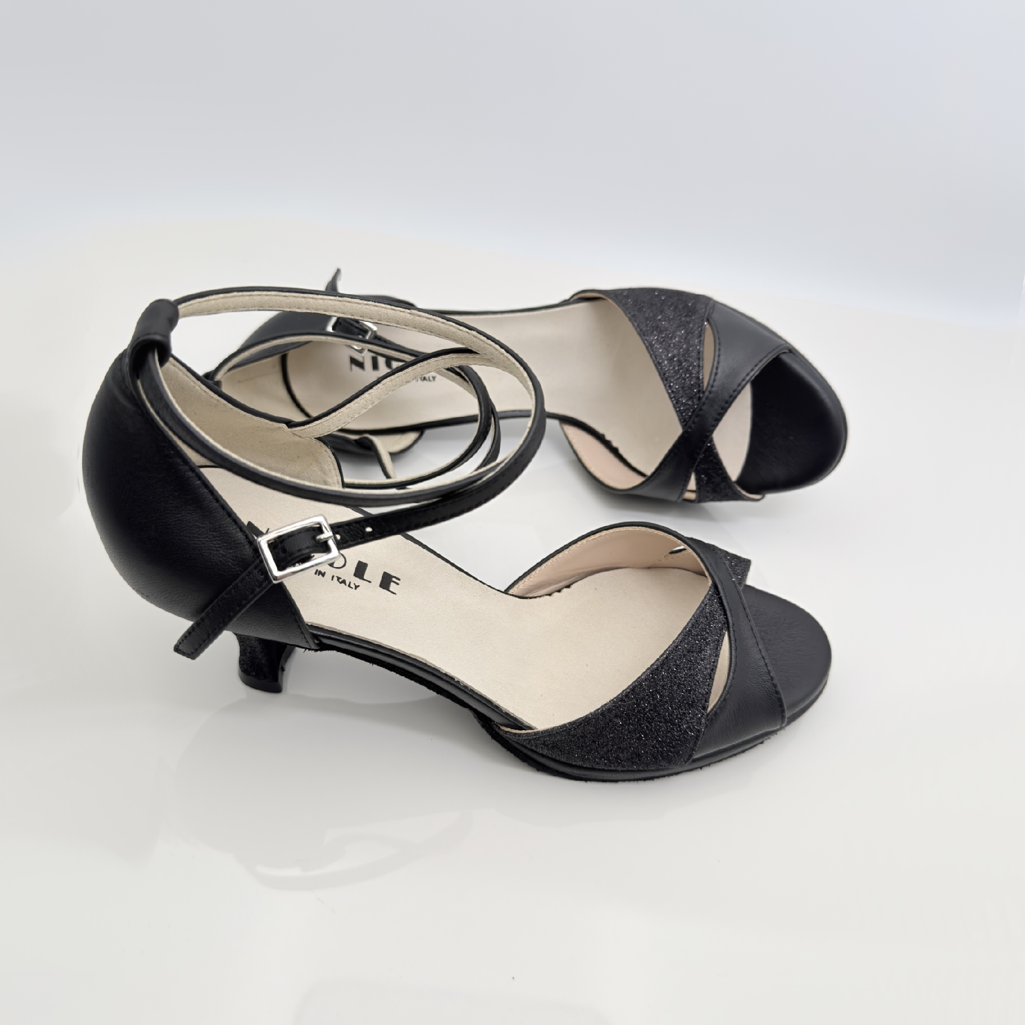 Dettaglio tomaia Elisa art. 117 fascia farfalla avvolgente pianta larga punta aperta F1P2 cinturino incrociato 2CAI pelle nera glitter fine nero tacco rocchetto 5HR plateau 1cm suola bufala Nicole Rimini made in Italy
